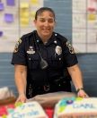 Officer Amy Bosse in uniform holding up two DARE cakies